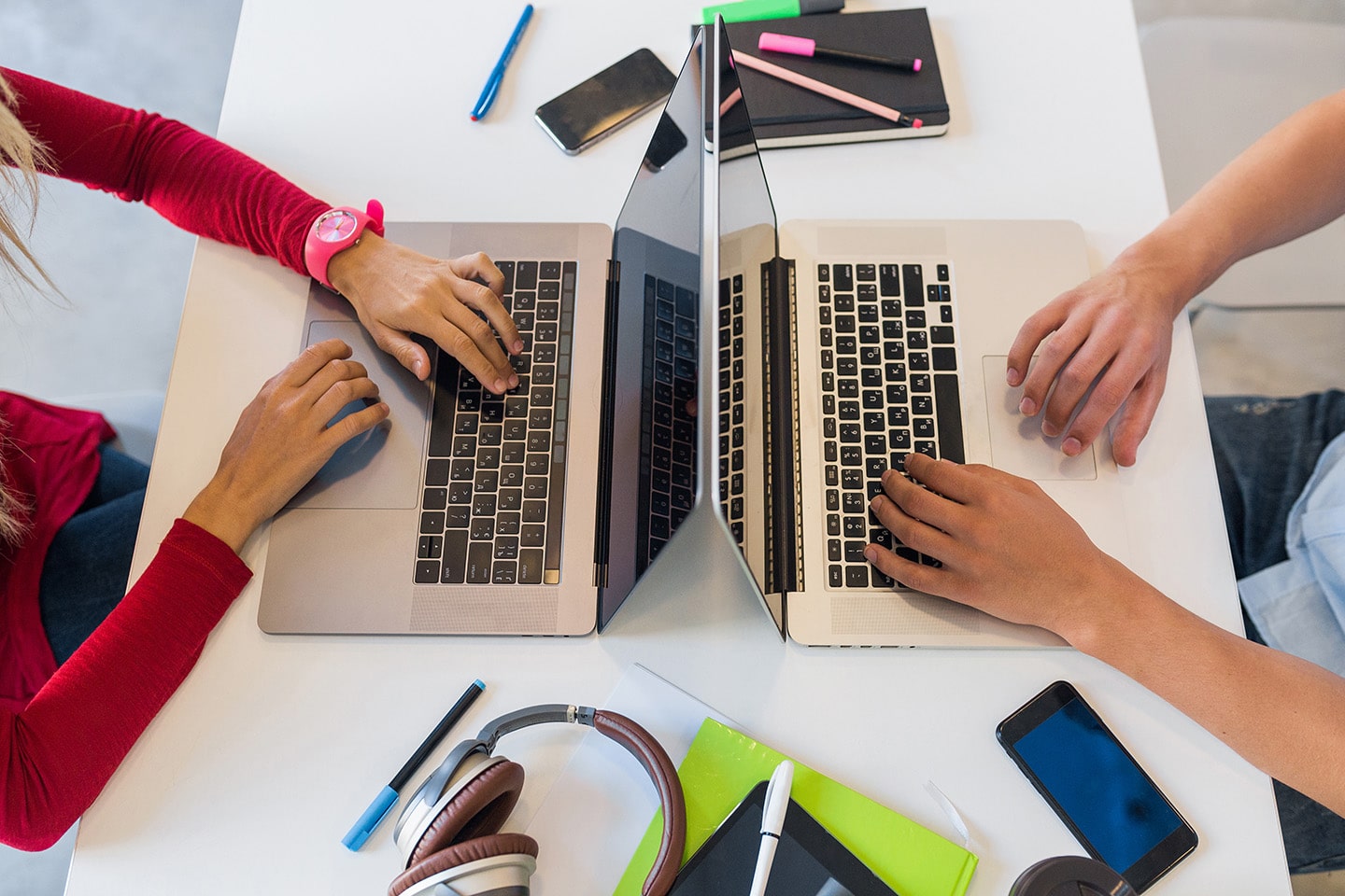 Métiers du numérique formation en alternance - Blog - Vue de dessus des mains du jeune homme et femme travaillant à l'ordinateur portable dans le bureau de travail collaboratif, en tapant sur le clavier